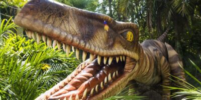 A dinosaur in front of a palm tree