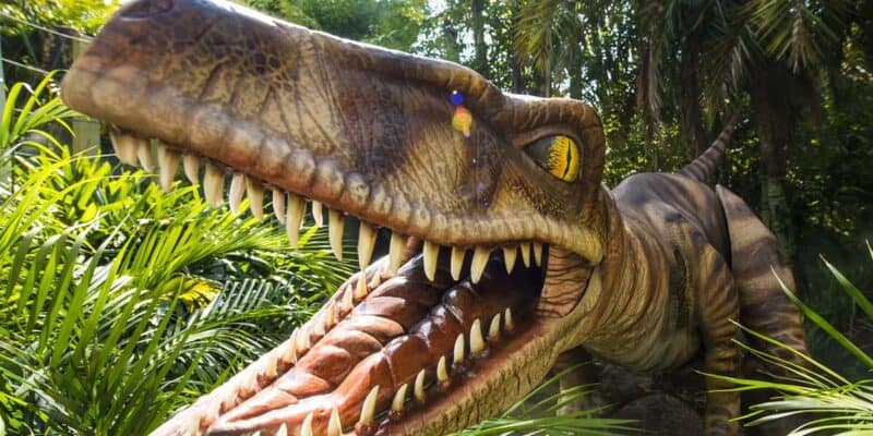 A dinosaur in front of a palm tree