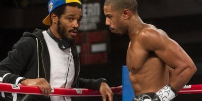 A coach in a track jacket gives guidance to a boxer wearing gloves and training gear inside a themed boxing ring, capturing the thrilling spirit of Marvel’s Black Panther-inspired experiences found at major entertainment resorts.