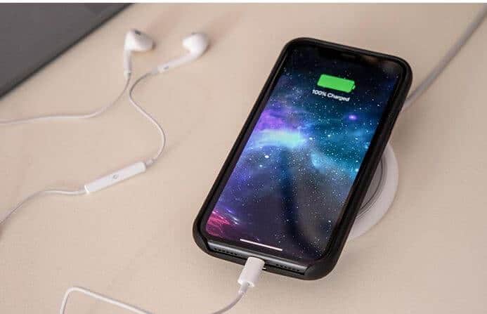 A cell phone with earphones on a charger