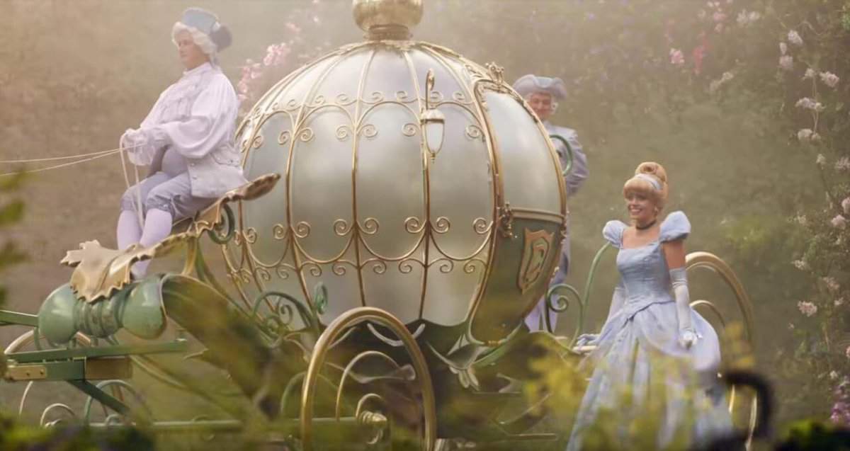Cinderella walks next to a carriage with a driver
