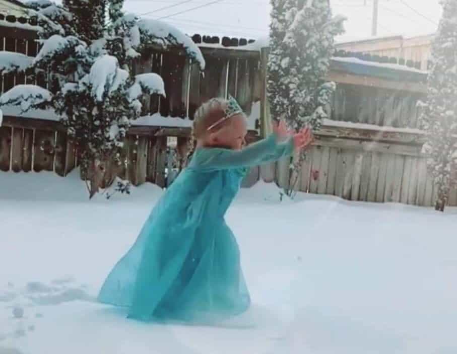 A little girl dressed as a princess standing in the snow