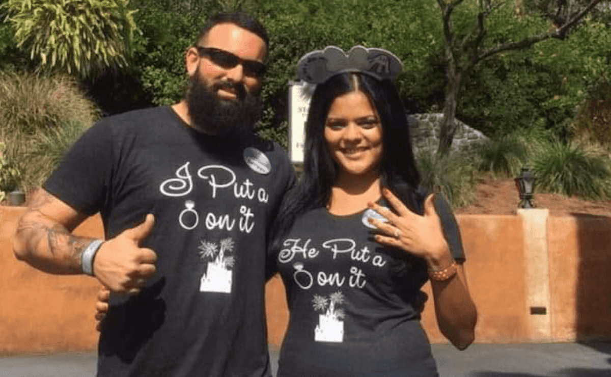 A man and a woman dressed in black showing they got engaged