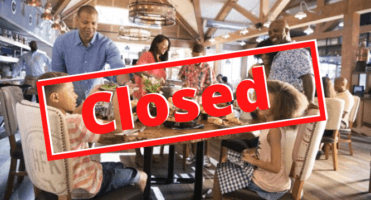 A group of people sitting in a restaurant and Closed sign