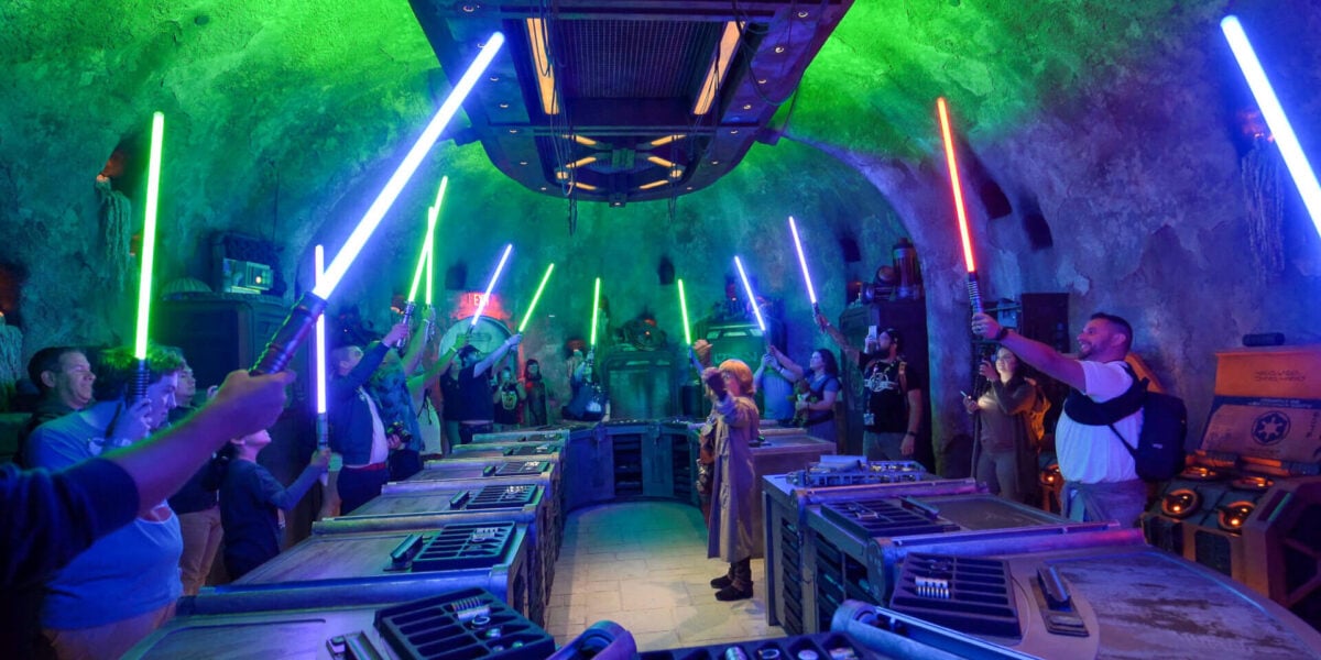 guests holding up newly built lightsabers at savi's workshop at star wars: galaxy's edge