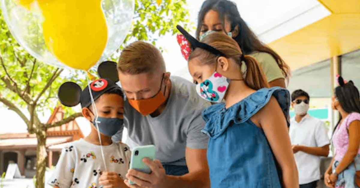 A group of people in Disney watching a cellphone