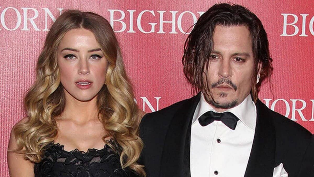 Amber Heard, Johnny Depp standing in front of a sign