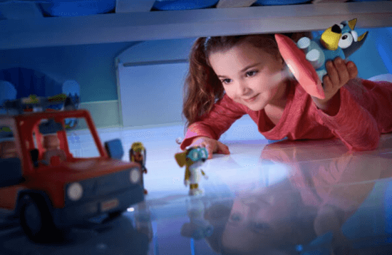 little girl playing with disney junior bluey toys