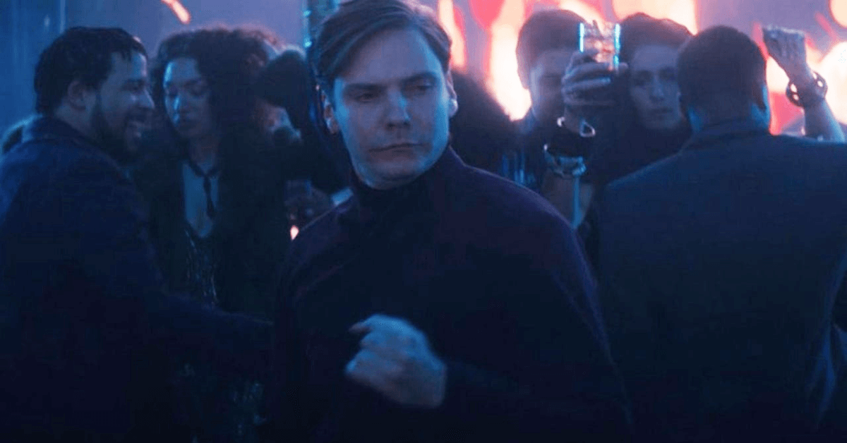 Daniel Bruhl standing in front of a crowd of people in a dark room
