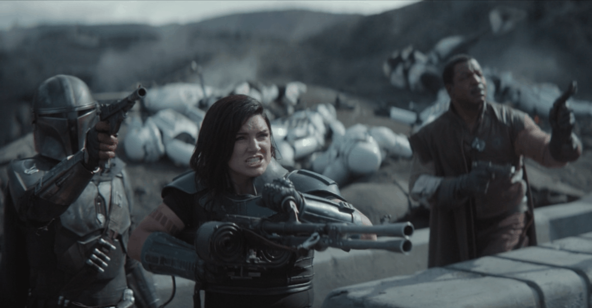 L-R: Din Djarin, Cara Dune, and Greef Karga all pointing blasters to the sky