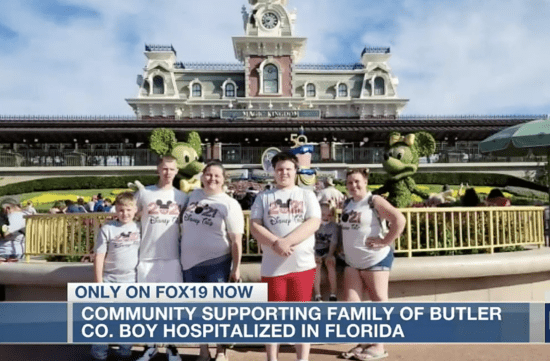 A group of people standing in front of Disney entrance