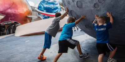 Kids pushing a giant moon in the World Discovery neighborhood.