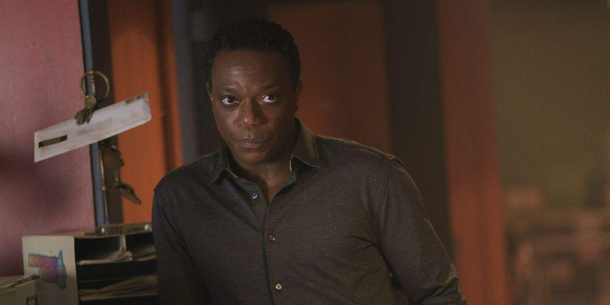 Clemson Murn (Chukwudi Iwuji) leaning on dresser in Peacemaker