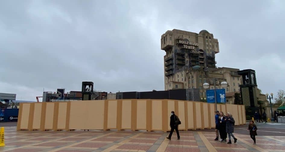 Construction walls surround the entrance to the iconic Hollywood Tower Hotel at Disney Park on a cloudy day, signaling behind-the-scenes changes and renovations, as guests stroll past and check out what’s new in this popular corner of the park.