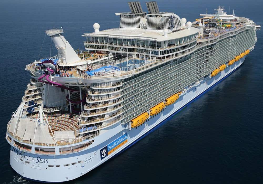 A large Florida cruise ship, untouched by any accident, sails on calm blue waters. The vessel boasts multiple decks, several pools, and water slides. It features an open area in the center, numerous balconies, and a distinctive blue and white color scheme.