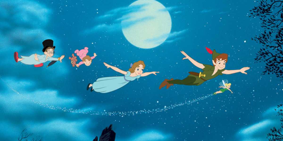 Animated scene featuring four children and a fairy flying in the night sky against a backdrop of a full moon. The children, in their nightclothes, are led by one dressed in green, reminiscent of Peter Pan. A glowing fairy beside them leaves a trail of sparkles.
