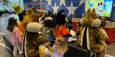 Goofy, Chip, Dale, and Max watch a Mickey short with kids at All-Star-Sports Resort.