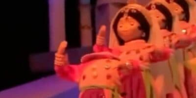 Three vibrant dolls dressed in traditional outfits stand side by side, each giving a thumbs up just like the cheerful animatronics from “it’s a small world” at Disneyland.