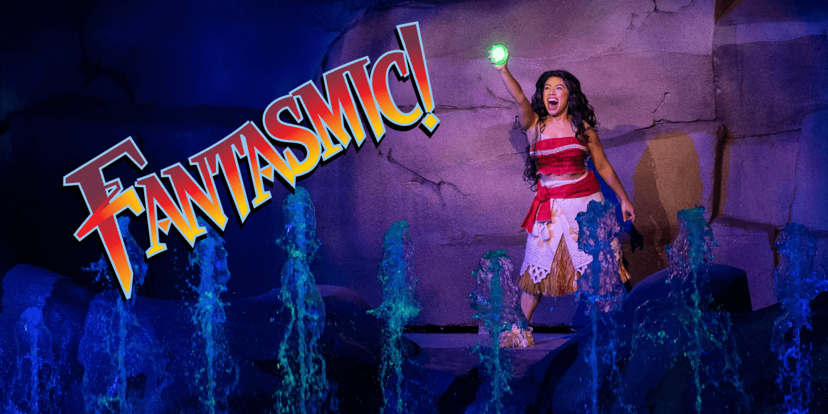 Moana holding up a glowing green orb while fountains go off in front of her. The Fantasmic! logo has been added over the photo.