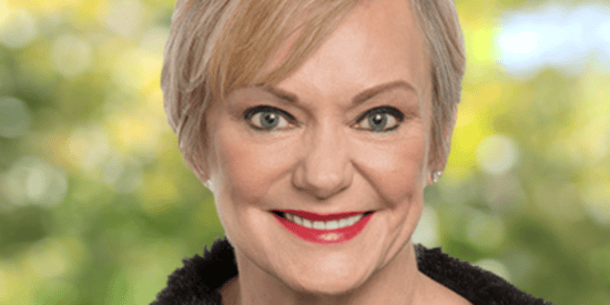 Christine McCarthy poses in front of trees, wearing a black fur-lined jacket.