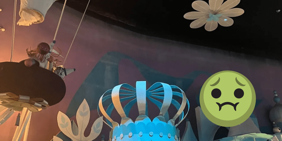 A grey substance on the walls of "it's a small world." A grossed out, green-faced emoji has been added onto the photo in post production.