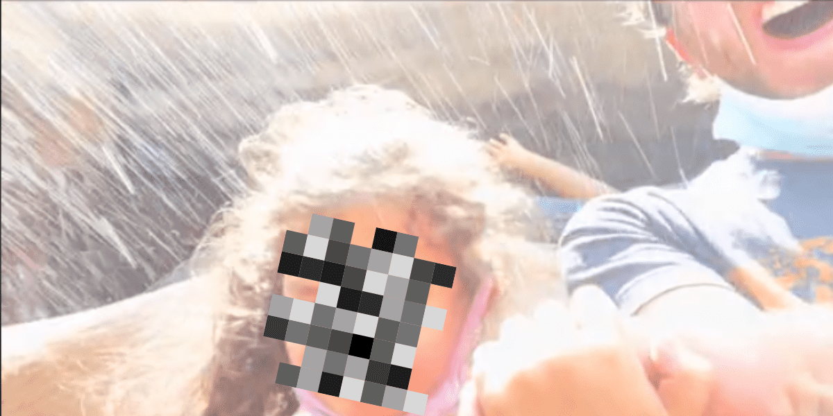 A little girl (face censored) shields herself from the water on splash mountain while her dad smiles.