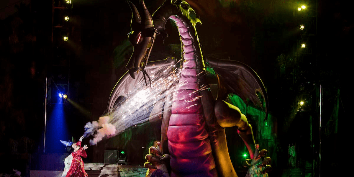 Micke Mouse in his Sorcerer's Apprentice outfit battling Maleficent as a dragon on Fantasmic