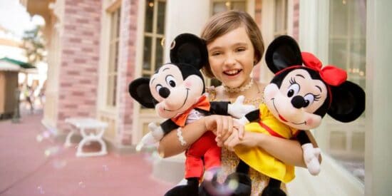 A child hugs Mickey and Minnie toys at Disney World