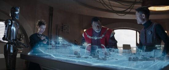 (L-R): A design droid, Civic Engineer (Maya Ramsey), Greef Karga (Carl Weathers) and Civic Engineer (London Kim) in Lucasfilm's THE MANDALORIAN, season three, exclusively on Disney+. ©2023 Lucasfilm Ltd. & TM. All Rights Reserved.
