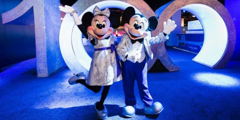 Mickey and Minnie in front of the Disney100 sign