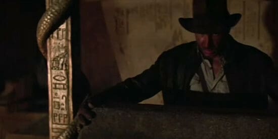 Harrison Ford as Indiana Jones next to an engraving of C-3PO and R2D2 in Raiders of the Lost Ark