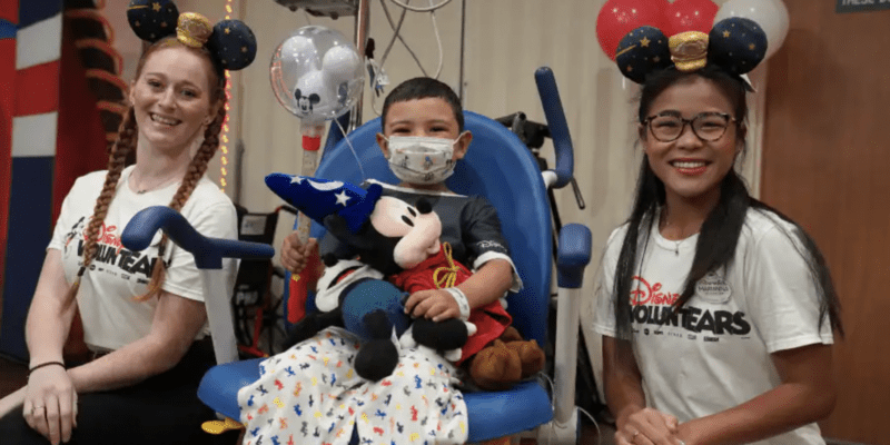 Two Cast Members pose with a child at a children's hospital