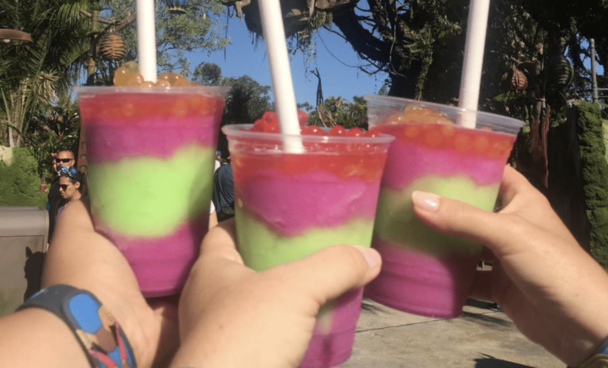 Three hands holding three Night Blossom drinks