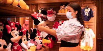 A female Cast Member holds up a Minnie Mouse plush