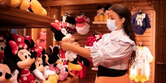 A female Disney Cast Member holds up a Minnie Mouse plush
