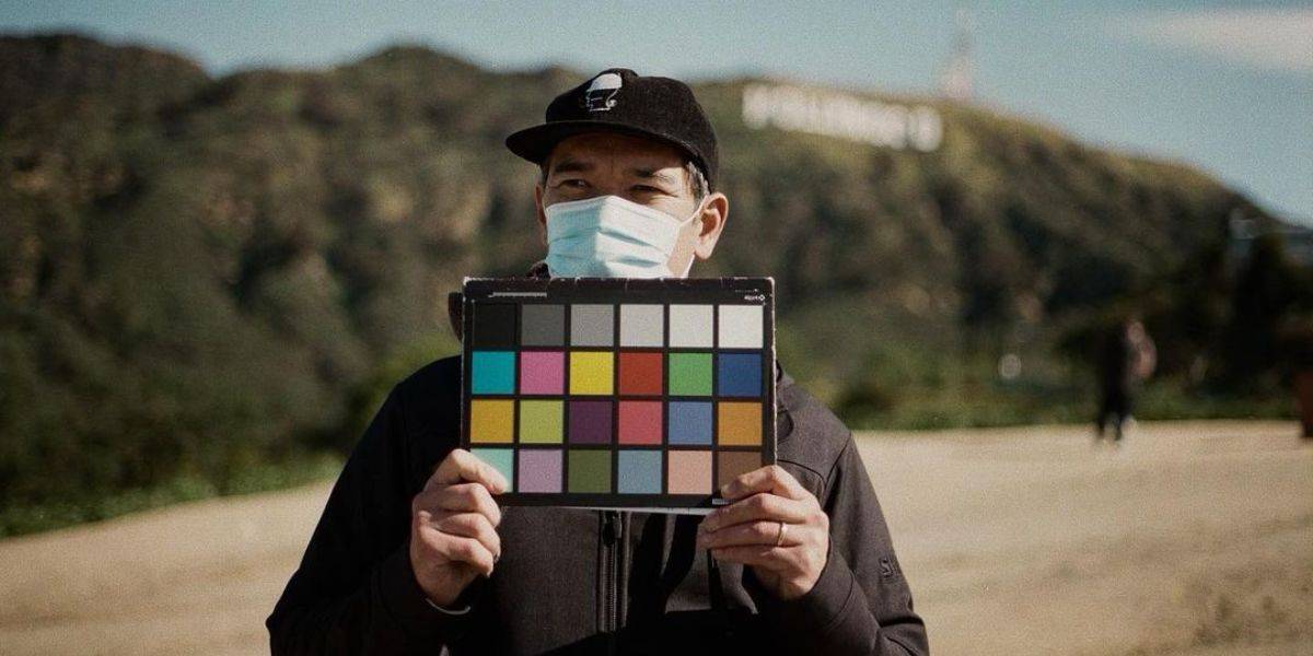 Daniel Cretton holds up a colorful sign in front of the Hollywood sign