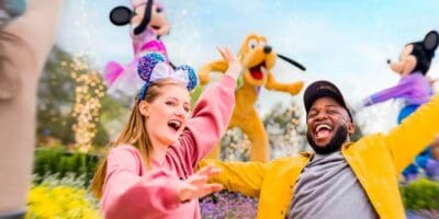 Female and male guest dance in front of Minnie, Pluto, and Mickey