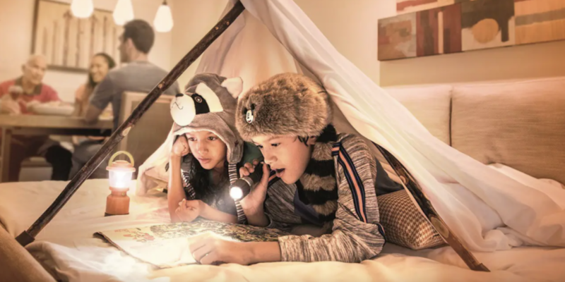 Two kids read under a blanket fort