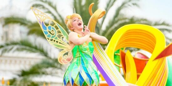 Tinker Bell clasps her hands on a colorful parade float