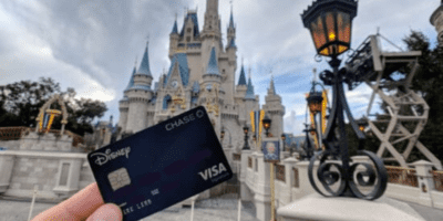 A credit card held up in front of Cinderella Castle at Walt Disney World.