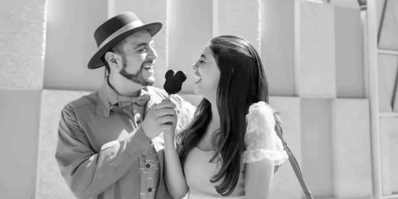 A man and a woman share a Mickey ice cream bar at Disneyland After Dark: Throwback Nite. The image is black & white.
