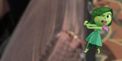 Disgust sticks her tongue out at a blurred image of a chair at Walt Disney World.