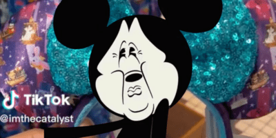 Mickey Mouse makes a disgusted face, covering up a pair of Tinkerbell Mickey Ears.