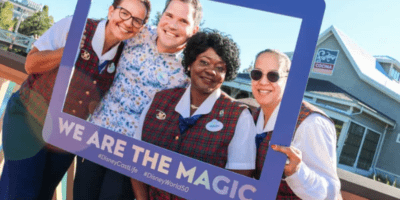 Disney cast members posing in a frame that reads "we are the magic"