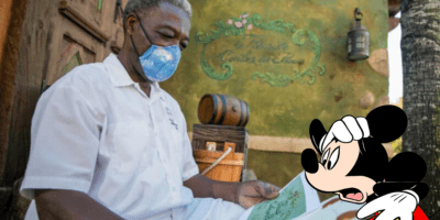 A Cast Member wearing a face mask to prevent the spread of disease at Disney World with Mickey Mouse scared