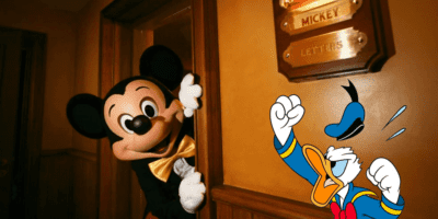 Donald Duck yells at Mickey Mouse hiding behind a door to avoid political protests