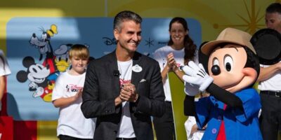 Josh D'Amaro claps next to Mickey Mouse