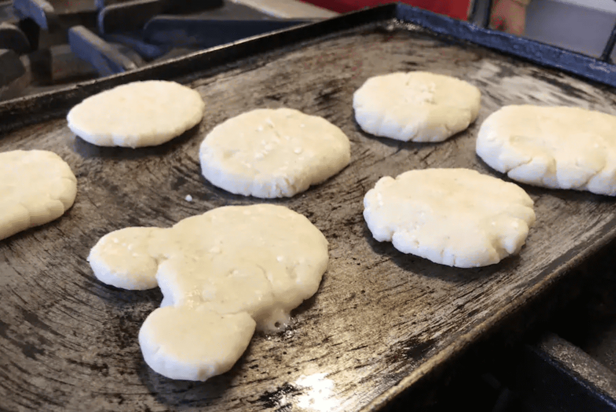 Arepas on a griddle, including a Mickey shaped arepa