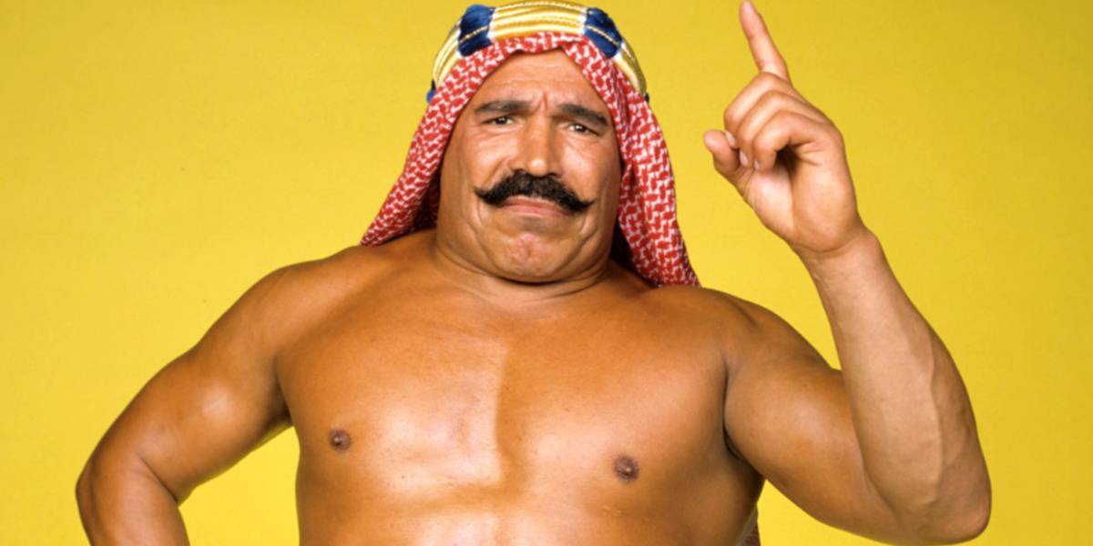WWE Legend Iron Sheik poses in front of a yellow background