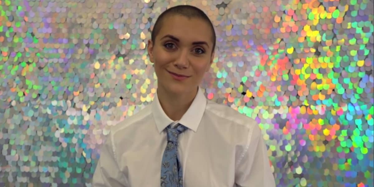 Alyson Stoner in a shirt and tie in front of a sparkly wall